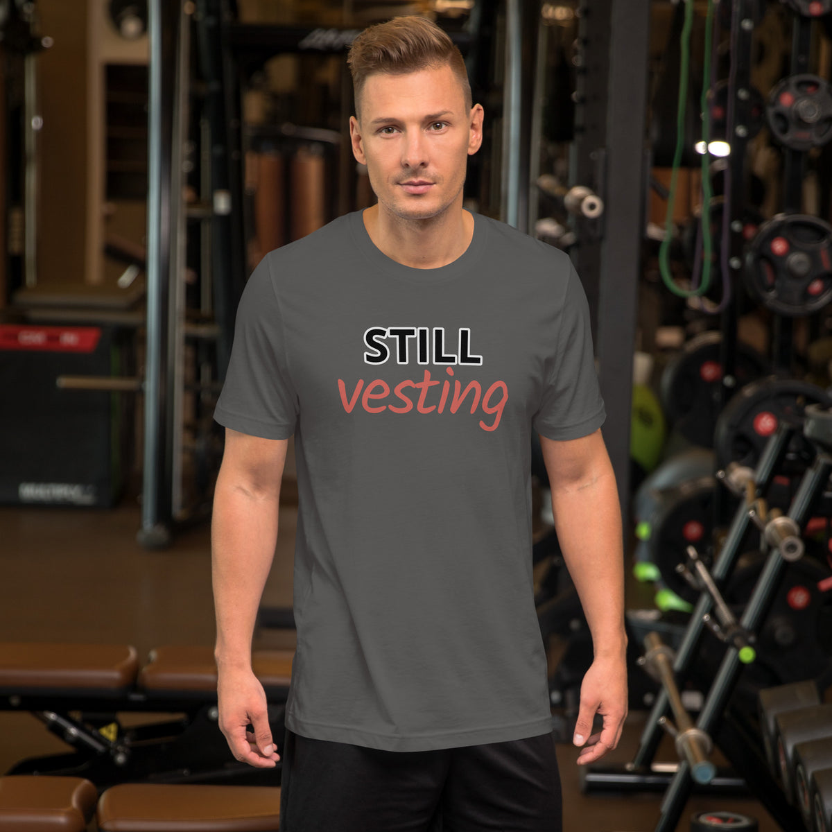Male model wearing charcoal t-shirt with bold white 'STILL' and rust-orange script 'vesting'